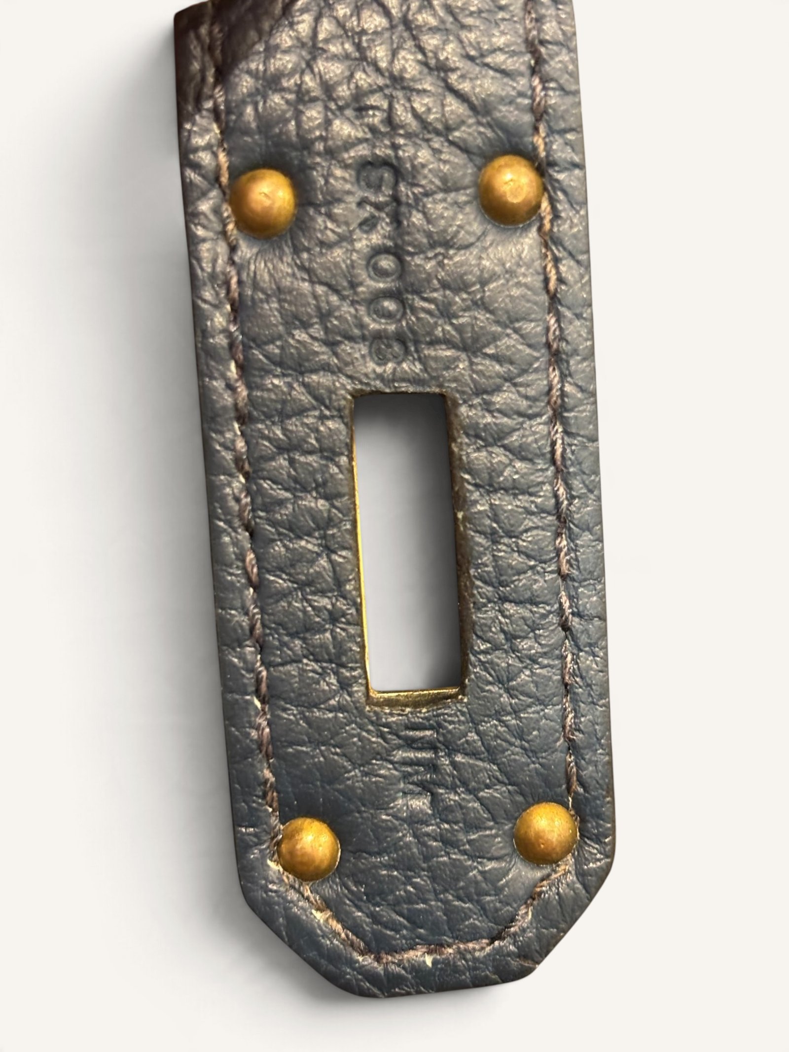 # Hermès HAC 40 Bleu de Prusse en cuir Togo, finitions Gold – 2015 Ce **HAC 40 Bleu de Prusse** en cuir Togo date de **2015**. Il se distingue par son magnifique bleu profond, associé à des **finitions Gold** qui apportent un contraste chaleureux. Présenté en **très bon état général**, cet exemplaire possède uniquement de légères traces d'utilisation au niveau des coins. Son format 40 et sa silhouette caractéristique lui confèrent une présence remarquable. **Dimensions : format 40 cm – dimensions complètes à compléter** **Matière : cuir Togo** **Couleur : Bleu de Prusse** **Finitions : Gold** **Année : 2015** **État : très bon état général, légères traces aux coins** Cette configuration associe l'élégance d'une couleur profonde à la texture du cuir Togo. Ainsi, le sac conserve une esthétique intemporelle tout en se distinguant des coloris plus traditionnels. --- ## HAC 40 Bleu de Prusse : une couleur profonde et élégante Le **Bleu de Prusse** fait partie des tonalités sombres particulièrement intéressantes de la palette Hermès. Sa profondeur lui donne une élégance proche de celle d'un bleu nuit. Cependant, ses nuances peuvent évoluer selon la lumière. Sous un éclairage naturel, le cuir peut révéler davantage de bleu. En revanche, dans une ambiance plus sombre, sa couleur apparaît plus intense. Cette richesse visuelle apporte une personnalité particulière au sac. De plus, le Bleu de Prusse s'associe facilement au noir, au gris, au beige et aux tons naturels. Il constitue donc une belle alternative aux grands sacs Hermès noirs ou marron. ## Le cuir Togo : une matière emblématique Le **cuir Togo** est apprécié pour son grain visible et son toucher souple. Il offre un équilibre intéressant entre structure et souplesse. Sur un grand format comme le HAC 40, cette matière permet de mettre en valeur les volumes du sac. Par ailleurs, sa surface grainée rend généralement les petites marques moins apparentes que sur certains cuirs lisses. Le résultat est un sac agréable à utiliser, tout en conservant une belle présence. Associé au Bleu de Prusse, le Togo révèle également de subtils jeux de lumière. ## Des finitions Gold au contraste raffiné Les **finitions Gold** jouent un rôle essentiel dans l'esthétique de cet exemplaire. Leur tonalité dorée contraste avec le bleu profond du cuir. Ainsi, les éléments métalliques deviennent de véritables détails décoratifs. Cette association apporte davantage de chaleur qu'une configuration accompagnée de finitions Palladium. De plus, le contraste entre le bleu et l'or renforce le caractère sophistiqué de ce HAC 40. Il s'agit d'une combinaison particulièrement élégante pour un grand sac de maroquinerie. ## Hermès HAC 40 : une silhouette historique Le **HAC**, ou *Haut à Courroies*, occupe une place particulière dans l'histoire d'Hermès. Créé à la fin du XIXe siècle, il était initialement destiné au transport des équipements équestres. Son nom fait référence à sa silhouette haute et à son système de fermeture à courroies. Au fil du temps, le modèle a évolué pour devenir une pièce emblématique de la maroquinerie de voyage Hermès. Aujourd'hui, il séduit aussi bien les collectionneurs que les amateurs de grands sacs de luxe. Son format généreux et sa structure reconnaissable lui donnent une identité distincte du Birkin. ## Un HAC 40 datant de 2015 Cet exemplaire a été fabriqué en **2015**. Il possède donc plus de dix années d'ancienneté. Malgré son âge, il est conservé dans un **très bon état général**. Seules de légères traces sont visibles au niveau des coins. Ces marques correspondent à une utilisation normale et restent limitées. Par ailleurs, elles sont clairement présentées afin de permettre une acquisition en toute transparence. ## Très bon état avec de légères traces aux coins L'état de conservation constitue un critère essentiel pour un sac Hermès d'occasion. Ce **HAC 40 Bleu de Prusse** est proposé en très bon état général. Le cuir Togo conserve une belle présentation. Cependant, quelques légères marques sont présentes aux coins. Ces zones sont naturellement exposées aux frottements lors de l'utilisation d'un sac. Nos photographies détaillées permettent donc d'apprécier précisément leur importance. Ainsi, l'acheteur dispose d'une description fidèle de l'état réel de la pièce. ## Le format HAC 40 : volume et élégance Le **format 40** offre un volume généreux. Il permet de transporter facilement de nombreux effets personnels. Ce sac peut notamment accueillir : - Un portefeuille. - Un téléphone. - Des lunettes. - Une pochette. - Des documents. - Une tablette. - Divers accessoires personnels. De plus, sa silhouette haute lui donne une présence plus affirmée que celle d'un sac à main classique. Il peut donc être envisagé comme un grand sac quotidien ou un élégant compagnon de déplacement. ## Un grand sac Hermès au caractère affirmé Le HAC 40 possède une esthétique immédiatement reconnaissable. Sa silhouette structurée et ses proportions généreuses lui confèrent une allure particulière. Sur cet exemplaire, le cuir Togo Bleu de Prusse apporte davantage de souplesse visuelle. En parallèle, les finitions Gold soulignent les lignes du sac. Ainsi, l'ensemble reste élégant malgré son volume important. Cette combinaison conviendra particulièrement aux amateurs de pièces Hermès discrètes par leur couleur, mais remarquables par leur format. ## Pourquoi choisir un HAC 40 Bleu de Prusse ? Cet exemplaire réunit plusieurs caractéristiques intéressantes : - **Modèle :** Hermès Haut à Courroies 40. - **Année :** 2015. - **Matière :** cuir Togo. - **Couleur :** Bleu de Prusse. - **Finitions :** Gold. - **État :** très bon état général. - **À noter :** légères traces d'utilisation aux coins. - **Format :** 40 cm. Cette configuration se distingue notamment par son équilibre entre couleur profonde, cuir grainé et finitions dorées. Elle constitue donc une belle option pour enrichir une collection Hermès ou acquérir un grand sac élégant. ## Une alternative aux HAC noirs et marron Les grands sacs Hermès sont souvent recherchés dans des couleurs classiques. Le noir, le Gold ou l'Ébène restent naturellement des choix intemporels. Toutefois, le Bleu de Prusse permet d'apporter davantage de personnalité sans choisir une couleur trop vive. Son intensité reste discrète. De plus, les finitions Gold créent un contraste qui souligne parfaitement le bleu du cuir. Ainsi, ce HAC 40 constitue une alternative particulièrement intéressante aux configurations traditionnelles. ## Un sac Hermès à porter et à conserver Grâce à son cuir Togo et à son format généreux, cet exemplaire peut être utilisé régulièrement. Il peut accompagner un vestiaire élégant ou plus décontracté. Cependant, sa couleur particulière lui donne également un intérêt pour les amateurs de configurations Hermès moins courantes. Le Bleu de Prusse permet notamment de varier une collection composée de sacs noirs, marron ou beiges. Ce HAC 40 peut donc aussi bien devenir un sac personnel qu'une belle pièce de collection. ## Pourquoi acheter votre HAC Hermès chez The Vintage Traveler ? Chez **The Vintage Traveler**, nous sélectionnons des sacs Hermès vintage et d'occasion pour leur authenticité, leur qualité et leurs caractéristiques. Chaque pièce est examinée avec attention afin de présenter précisément son état et ses particularités. ### Nos garanties ✔ **Magasin physique situé au Marché Paul Bert Serpette**, au cœur des Puces de Saint-Ouen. ✔ Sac **expertisé et certifié authentique** par un spécialiste du luxe vintage et d'occasion. ✔ Certificat d'authenticité fourni avec votre achat. ✔ Photographies détaillées et fidèles à l'état réel du sac. ✔ Description transparente des légères traces présentes aux coins. ✔ Accompagnement personnalisé avant et après votre achat. ✔ Expédition internationale rapide, sécurisée et assurée. --- ## Caractéristiques du Hermès HAC 40 **Maison :** Hermès **Modèle :** Haut à Courroies – HAC 40 **Année :** 2015 **Matière :** Cuir Togo **Couleur :** Bleu de Prusse **Finitions :** Gold **Format :** 40 cm **Dimensions complètes :** à compléter **État :** Très bon état général **À noter :** Légères traces d'utilisation aux coins --- ## Un élégant HAC 40 Bleu de Prusse de 2015 Ce **HAC 40 Bleu de Prusse** en cuir Togo constitue une superbe interprétation du célèbre Haut à Courroies Hermès. Sa couleur profonde, associée aux **finitions Gold**, lui donne une esthétique particulièrement raffinée. Datant de **2015**, cet exemplaire est conservé dans un **très bon état général**, avec seulement de légères traces aux coins. Enfin, son format 40 offre un volume généreux tout en conservant la silhouette emblématique du HAC. Une belle pièce pour les amateurs de **sacs Hermès d'occasion**, de grands formats et de couleurs sophistiquées.
