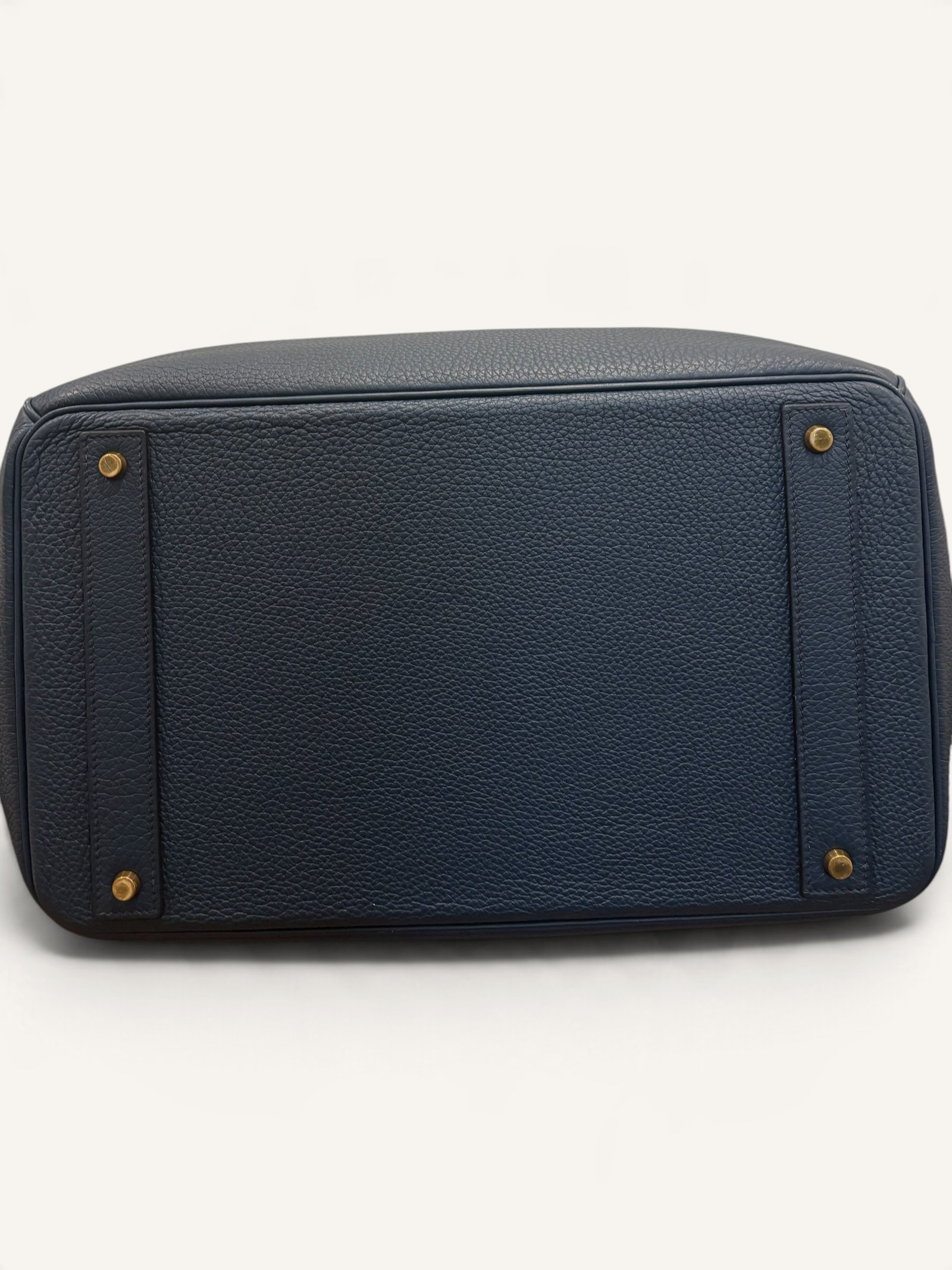 # Hermès HAC 40 Bleu de Prusse en cuir Togo, finitions Gold – 2015 Ce **HAC 40 Bleu de Prusse** en cuir Togo date de **2015**. Il se distingue par son magnifique bleu profond, associé à des **finitions Gold** qui apportent un contraste chaleureux. Présenté en **très bon état général**, cet exemplaire possède uniquement de légères traces d'utilisation au niveau des coins. Son format 40 et sa silhouette caractéristique lui confèrent une présence remarquable. **Dimensions : format 40 cm – dimensions complètes à compléter** **Matière : cuir Togo** **Couleur : Bleu de Prusse** **Finitions : Gold** **Année : 2015** **État : très bon état général, légères traces aux coins** Cette configuration associe l'élégance d'une couleur profonde à la texture du cuir Togo. Ainsi, le sac conserve une esthétique intemporelle tout en se distinguant des coloris plus traditionnels. --- ## HAC 40 Bleu de Prusse : une couleur profonde et élégante Le **Bleu de Prusse** fait partie des tonalités sombres particulièrement intéressantes de la palette Hermès. Sa profondeur lui donne une élégance proche de celle d'un bleu nuit. Cependant, ses nuances peuvent évoluer selon la lumière. Sous un éclairage naturel, le cuir peut révéler davantage de bleu. En revanche, dans une ambiance plus sombre, sa couleur apparaît plus intense. Cette richesse visuelle apporte une personnalité particulière au sac. De plus, le Bleu de Prusse s'associe facilement au noir, au gris, au beige et aux tons naturels. Il constitue donc une belle alternative aux grands sacs Hermès noirs ou marron. ## Le cuir Togo : une matière emblématique Le **cuir Togo** est apprécié pour son grain visible et son toucher souple. Il offre un équilibre intéressant entre structure et souplesse. Sur un grand format comme le HAC 40, cette matière permet de mettre en valeur les volumes du sac. Par ailleurs, sa surface grainée rend généralement les petites marques moins apparentes que sur certains cuirs lisses. Le résultat est un sac agréable à utiliser, tout en conservant une belle présence. Associé au Bleu de Prusse, le Togo révèle également de subtils jeux de lumière. ## Des finitions Gold au contraste raffiné Les **finitions Gold** jouent un rôle essentiel dans l'esthétique de cet exemplaire. Leur tonalité dorée contraste avec le bleu profond du cuir. Ainsi, les éléments métalliques deviennent de véritables détails décoratifs. Cette association apporte davantage de chaleur qu'une configuration accompagnée de finitions Palladium. De plus, le contraste entre le bleu et l'or renforce le caractère sophistiqué de ce HAC 40. Il s'agit d'une combinaison particulièrement élégante pour un grand sac de maroquinerie. ## Hermès HAC 40 : une silhouette historique Le **HAC**, ou *Haut à Courroies*, occupe une place particulière dans l'histoire d'Hermès. Créé à la fin du XIXe siècle, il était initialement destiné au transport des équipements équestres. Son nom fait référence à sa silhouette haute et à son système de fermeture à courroies. Au fil du temps, le modèle a évolué pour devenir une pièce emblématique de la maroquinerie de voyage Hermès. Aujourd'hui, il séduit aussi bien les collectionneurs que les amateurs de grands sacs de luxe. Son format généreux et sa structure reconnaissable lui donnent une identité distincte du Birkin. ## Un HAC 40 datant de 2015 Cet exemplaire a été fabriqué en **2015**. Il possède donc plus de dix années d'ancienneté. Malgré son âge, il est conservé dans un **très bon état général**. Seules de légères traces sont visibles au niveau des coins. Ces marques correspondent à une utilisation normale et restent limitées. Par ailleurs, elles sont clairement présentées afin de permettre une acquisition en toute transparence. ## Très bon état avec de légères traces aux coins L'état de conservation constitue un critère essentiel pour un sac Hermès d'occasion. Ce **HAC 40 Bleu de Prusse** est proposé en très bon état général. Le cuir Togo conserve une belle présentation. Cependant, quelques légères marques sont présentes aux coins. Ces zones sont naturellement exposées aux frottements lors de l'utilisation d'un sac. Nos photographies détaillées permettent donc d'apprécier précisément leur importance. Ainsi, l'acheteur dispose d'une description fidèle de l'état réel de la pièce. ## Le format HAC 40 : volume et élégance Le **format 40** offre un volume généreux. Il permet de transporter facilement de nombreux effets personnels. Ce sac peut notamment accueillir : - Un portefeuille. - Un téléphone. - Des lunettes. - Une pochette. - Des documents. - Une tablette. - Divers accessoires personnels. De plus, sa silhouette haute lui donne une présence plus affirmée que celle d'un sac à main classique. Il peut donc être envisagé comme un grand sac quotidien ou un élégant compagnon de déplacement. ## Un grand sac Hermès au caractère affirmé Le HAC 40 possède une esthétique immédiatement reconnaissable. Sa silhouette structurée et ses proportions généreuses lui confèrent une allure particulière. Sur cet exemplaire, le cuir Togo Bleu de Prusse apporte davantage de souplesse visuelle. En parallèle, les finitions Gold soulignent les lignes du sac. Ainsi, l'ensemble reste élégant malgré son volume important. Cette combinaison conviendra particulièrement aux amateurs de pièces Hermès discrètes par leur couleur, mais remarquables par leur format. ## Pourquoi choisir un HAC 40 Bleu de Prusse ? Cet exemplaire réunit plusieurs caractéristiques intéressantes : - **Modèle :** Hermès Haut à Courroies 40. - **Année :** 2015. - **Matière :** cuir Togo. - **Couleur :** Bleu de Prusse. - **Finitions :** Gold. - **État :** très bon état général. - **À noter :** légères traces d'utilisation aux coins. - **Format :** 40 cm. Cette configuration se distingue notamment par son équilibre entre couleur profonde, cuir grainé et finitions dorées. Elle constitue donc une belle option pour enrichir une collection Hermès ou acquérir un grand sac élégant. ## Une alternative aux HAC noirs et marron Les grands sacs Hermès sont souvent recherchés dans des couleurs classiques. Le noir, le Gold ou l'Ébène restent naturellement des choix intemporels. Toutefois, le Bleu de Prusse permet d'apporter davantage de personnalité sans choisir une couleur trop vive. Son intensité reste discrète. De plus, les finitions Gold créent un contraste qui souligne parfaitement le bleu du cuir. Ainsi, ce HAC 40 constitue une alternative particulièrement intéressante aux configurations traditionnelles. ## Un sac Hermès à porter et à conserver Grâce à son cuir Togo et à son format généreux, cet exemplaire peut être utilisé régulièrement. Il peut accompagner un vestiaire élégant ou plus décontracté. Cependant, sa couleur particulière lui donne également un intérêt pour les amateurs de configurations Hermès moins courantes. Le Bleu de Prusse permet notamment de varier une collection composée de sacs noirs, marron ou beiges. Ce HAC 40 peut donc aussi bien devenir un sac personnel qu'une belle pièce de collection. ## Pourquoi acheter votre HAC Hermès chez The Vintage Traveler ? Chez **The Vintage Traveler**, nous sélectionnons des sacs Hermès vintage et d'occasion pour leur authenticité, leur qualité et leurs caractéristiques. Chaque pièce est examinée avec attention afin de présenter précisément son état et ses particularités. ### Nos garanties ✔ **Magasin physique situé au Marché Paul Bert Serpette**, au cœur des Puces de Saint-Ouen. ✔ Sac **expertisé et certifié authentique** par un spécialiste du luxe vintage et d'occasion. ✔ Certificat d'authenticité fourni avec votre achat. ✔ Photographies détaillées et fidèles à l'état réel du sac. ✔ Description transparente des légères traces présentes aux coins. ✔ Accompagnement personnalisé avant et après votre achat. ✔ Expédition internationale rapide, sécurisée et assurée. --- ## Caractéristiques du Hermès HAC 40 **Maison :** Hermès **Modèle :** Haut à Courroies – HAC 40 **Année :** 2015 **Matière :** Cuir Togo **Couleur :** Bleu de Prusse **Finitions :** Gold **Format :** 40 cm **Dimensions complètes :** à compléter **État :** Très bon état général **À noter :** Légères traces d'utilisation aux coins --- ## Un élégant HAC 40 Bleu de Prusse de 2015 Ce **HAC 40 Bleu de Prusse** en cuir Togo constitue une superbe interprétation du célèbre Haut à Courroies Hermès. Sa couleur profonde, associée aux **finitions Gold**, lui donne une esthétique particulièrement raffinée. Datant de **2015**, cet exemplaire est conservé dans un **très bon état général**, avec seulement de légères traces aux coins. Enfin, son format 40 offre un volume généreux tout en conservant la silhouette emblématique du HAC. Une belle pièce pour les amateurs de **sacs Hermès d'occasion**, de grands formats et de couleurs sophistiquées.