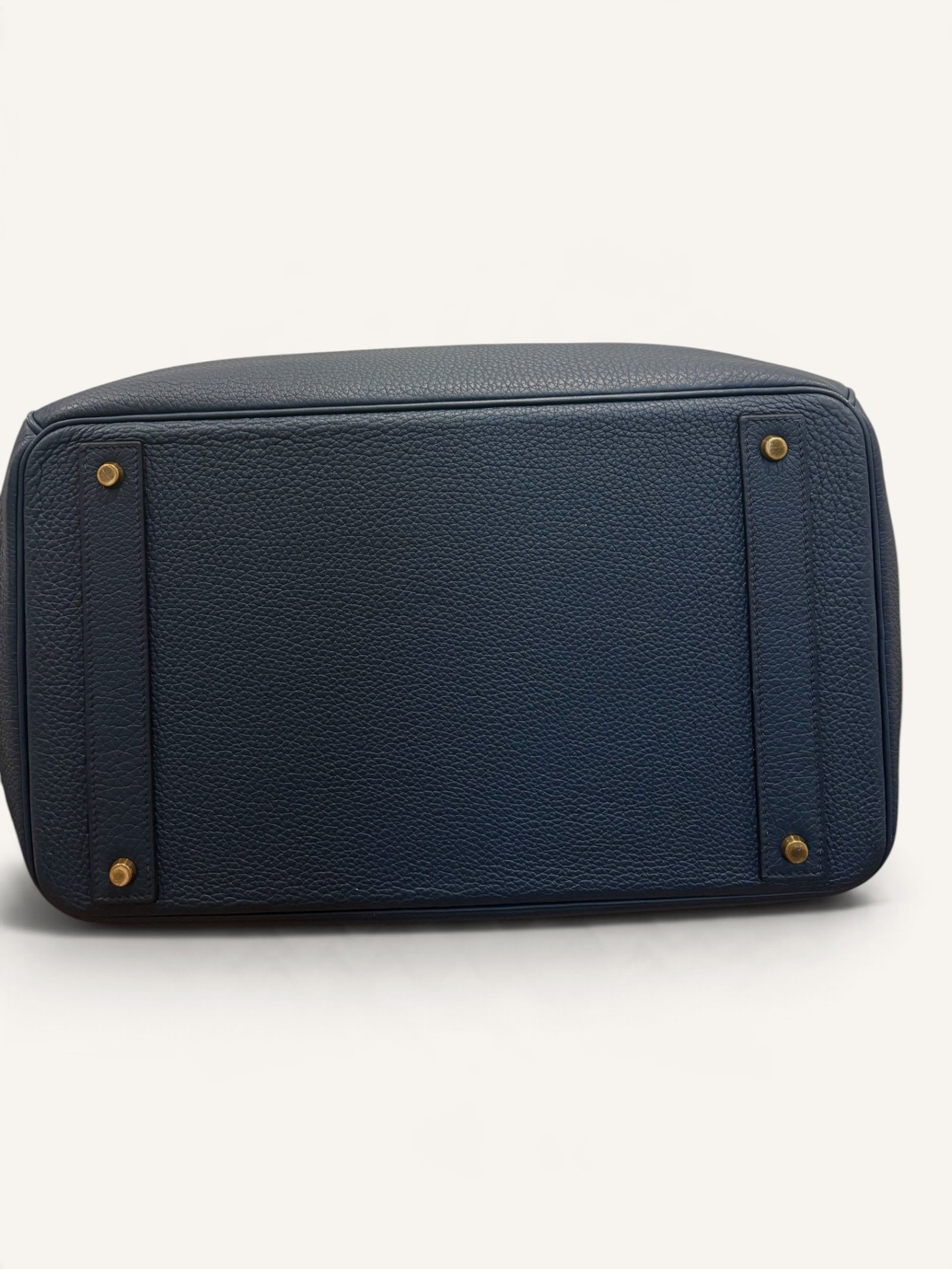 # Hermès HAC 40 Bleu de Prusse en cuir Togo, finitions Gold – 2015 Ce **HAC 40 Bleu de Prusse** en cuir Togo date de **2015**. Il se distingue par son magnifique bleu profond, associé à des **finitions Gold** qui apportent un contraste chaleureux. Présenté en **très bon état général**, cet exemplaire possède uniquement de légères traces d'utilisation au niveau des coins. Son format 40 et sa silhouette caractéristique lui confèrent une présence remarquable. **Dimensions : format 40 cm – dimensions complètes à compléter** **Matière : cuir Togo** **Couleur : Bleu de Prusse** **Finitions : Gold** **Année : 2015** **État : très bon état général, légères traces aux coins** Cette configuration associe l'élégance d'une couleur profonde à la texture du cuir Togo. Ainsi, le sac conserve une esthétique intemporelle tout en se distinguant des coloris plus traditionnels. --- ## HAC 40 Bleu de Prusse : une couleur profonde et élégante Le **Bleu de Prusse** fait partie des tonalités sombres particulièrement intéressantes de la palette Hermès. Sa profondeur lui donne une élégance proche de celle d'un bleu nuit. Cependant, ses nuances peuvent évoluer selon la lumière. Sous un éclairage naturel, le cuir peut révéler davantage de bleu. En revanche, dans une ambiance plus sombre, sa couleur apparaît plus intense. Cette richesse visuelle apporte une personnalité particulière au sac. De plus, le Bleu de Prusse s'associe facilement au noir, au gris, au beige et aux tons naturels. Il constitue donc une belle alternative aux grands sacs Hermès noirs ou marron. ## Le cuir Togo : une matière emblématique Le **cuir Togo** est apprécié pour son grain visible et son toucher souple. Il offre un équilibre intéressant entre structure et souplesse. Sur un grand format comme le HAC 40, cette matière permet de mettre en valeur les volumes du sac. Par ailleurs, sa surface grainée rend généralement les petites marques moins apparentes que sur certains cuirs lisses. Le résultat est un sac agréable à utiliser, tout en conservant une belle présence. Associé au Bleu de Prusse, le Togo révèle également de subtils jeux de lumière. ## Des finitions Gold au contraste raffiné Les **finitions Gold** jouent un rôle essentiel dans l'esthétique de cet exemplaire. Leur tonalité dorée contraste avec le bleu profond du cuir. Ainsi, les éléments métalliques deviennent de véritables détails décoratifs. Cette association apporte davantage de chaleur qu'une configuration accompagnée de finitions Palladium. De plus, le contraste entre le bleu et l'or renforce le caractère sophistiqué de ce HAC 40. Il s'agit d'une combinaison particulièrement élégante pour un grand sac de maroquinerie. ## Hermès HAC 40 : une silhouette historique Le **HAC**, ou *Haut à Courroies*, occupe une place particulière dans l'histoire d'Hermès. Créé à la fin du XIXe siècle, il était initialement destiné au transport des équipements équestres. Son nom fait référence à sa silhouette haute et à son système de fermeture à courroies. Au fil du temps, le modèle a évolué pour devenir une pièce emblématique de la maroquinerie de voyage Hermès. Aujourd'hui, il séduit aussi bien les collectionneurs que les amateurs de grands sacs de luxe. Son format généreux et sa structure reconnaissable lui donnent une identité distincte du Birkin. ## Un HAC 40 datant de 2015 Cet exemplaire a été fabriqué en **2015**. Il possède donc plus de dix années d'ancienneté. Malgré son âge, il est conservé dans un **très bon état général**. Seules de légères traces sont visibles au niveau des coins. Ces marques correspondent à une utilisation normale et restent limitées. Par ailleurs, elles sont clairement présentées afin de permettre une acquisition en toute transparence. ## Très bon état avec de légères traces aux coins L'état de conservation constitue un critère essentiel pour un sac Hermès d'occasion. Ce **HAC 40 Bleu de Prusse** est proposé en très bon état général. Le cuir Togo conserve une belle présentation. Cependant, quelques légères marques sont présentes aux coins. Ces zones sont naturellement exposées aux frottements lors de l'utilisation d'un sac. Nos photographies détaillées permettent donc d'apprécier précisément leur importance. Ainsi, l'acheteur dispose d'une description fidèle de l'état réel de la pièce. ## Le format HAC 40 : volume et élégance Le **format 40** offre un volume généreux. Il permet de transporter facilement de nombreux effets personnels. Ce sac peut notamment accueillir : - Un portefeuille. - Un téléphone. - Des lunettes. - Une pochette. - Des documents. - Une tablette. - Divers accessoires personnels. De plus, sa silhouette haute lui donne une présence plus affirmée que celle d'un sac à main classique. Il peut donc être envisagé comme un grand sac quotidien ou un élégant compagnon de déplacement. ## Un grand sac Hermès au caractère affirmé Le HAC 40 possède une esthétique immédiatement reconnaissable. Sa silhouette structurée et ses proportions généreuses lui confèrent une allure particulière. Sur cet exemplaire, le cuir Togo Bleu de Prusse apporte davantage de souplesse visuelle. En parallèle, les finitions Gold soulignent les lignes du sac. Ainsi, l'ensemble reste élégant malgré son volume important. Cette combinaison conviendra particulièrement aux amateurs de pièces Hermès discrètes par leur couleur, mais remarquables par leur format. ## Pourquoi choisir un HAC 40 Bleu de Prusse ? Cet exemplaire réunit plusieurs caractéristiques intéressantes : - **Modèle :** Hermès Haut à Courroies 40. - **Année :** 2015. - **Matière :** cuir Togo. - **Couleur :** Bleu de Prusse. - **Finitions :** Gold. - **État :** très bon état général. - **À noter :** légères traces d'utilisation aux coins. - **Format :** 40 cm. Cette configuration se distingue notamment par son équilibre entre couleur profonde, cuir grainé et finitions dorées. Elle constitue donc une belle option pour enrichir une collection Hermès ou acquérir un grand sac élégant. ## Une alternative aux HAC noirs et marron Les grands sacs Hermès sont souvent recherchés dans des couleurs classiques. Le noir, le Gold ou l'Ébène restent naturellement des choix intemporels. Toutefois, le Bleu de Prusse permet d'apporter davantage de personnalité sans choisir une couleur trop vive. Son intensité reste discrète. De plus, les finitions Gold créent un contraste qui souligne parfaitement le bleu du cuir. Ainsi, ce HAC 40 constitue une alternative particulièrement intéressante aux configurations traditionnelles. ## Un sac Hermès à porter et à conserver Grâce à son cuir Togo et à son format généreux, cet exemplaire peut être utilisé régulièrement. Il peut accompagner un vestiaire élégant ou plus décontracté. Cependant, sa couleur particulière lui donne également un intérêt pour les amateurs de configurations Hermès moins courantes. Le Bleu de Prusse permet notamment de varier une collection composée de sacs noirs, marron ou beiges. Ce HAC 40 peut donc aussi bien devenir un sac personnel qu'une belle pièce de collection. ## Pourquoi acheter votre HAC Hermès chez The Vintage Traveler ? Chez **The Vintage Traveler**, nous sélectionnons des sacs Hermès vintage et d'occasion pour leur authenticité, leur qualité et leurs caractéristiques. Chaque pièce est examinée avec attention afin de présenter précisément son état et ses particularités. ### Nos garanties ✔ **Magasin physique situé au Marché Paul Bert Serpette**, au cœur des Puces de Saint-Ouen. ✔ Sac **expertisé et certifié authentique** par un spécialiste du luxe vintage et d'occasion. ✔ Certificat d'authenticité fourni avec votre achat. ✔ Photographies détaillées et fidèles à l'état réel du sac. ✔ Description transparente des légères traces présentes aux coins. ✔ Accompagnement personnalisé avant et après votre achat. ✔ Expédition internationale rapide, sécurisée et assurée. --- ## Caractéristiques du Hermès HAC 40 **Maison :** Hermès **Modèle :** Haut à Courroies – HAC 40 **Année :** 2015 **Matière :** Cuir Togo **Couleur :** Bleu de Prusse **Finitions :** Gold **Format :** 40 cm **Dimensions complètes :** à compléter **État :** Très bon état général **À noter :** Légères traces d'utilisation aux coins --- ## Un élégant HAC 40 Bleu de Prusse de 2015 Ce **HAC 40 Bleu de Prusse** en cuir Togo constitue une superbe interprétation du célèbre Haut à Courroies Hermès. Sa couleur profonde, associée aux **finitions Gold**, lui donne une esthétique particulièrement raffinée. Datant de **2015**, cet exemplaire est conservé dans un **très bon état général**, avec seulement de légères traces aux coins. Enfin, son format 40 offre un volume généreux tout en conservant la silhouette emblématique du HAC. Une belle pièce pour les amateurs de **sacs Hermès d'occasion**, de grands formats et de couleurs sophistiquées.