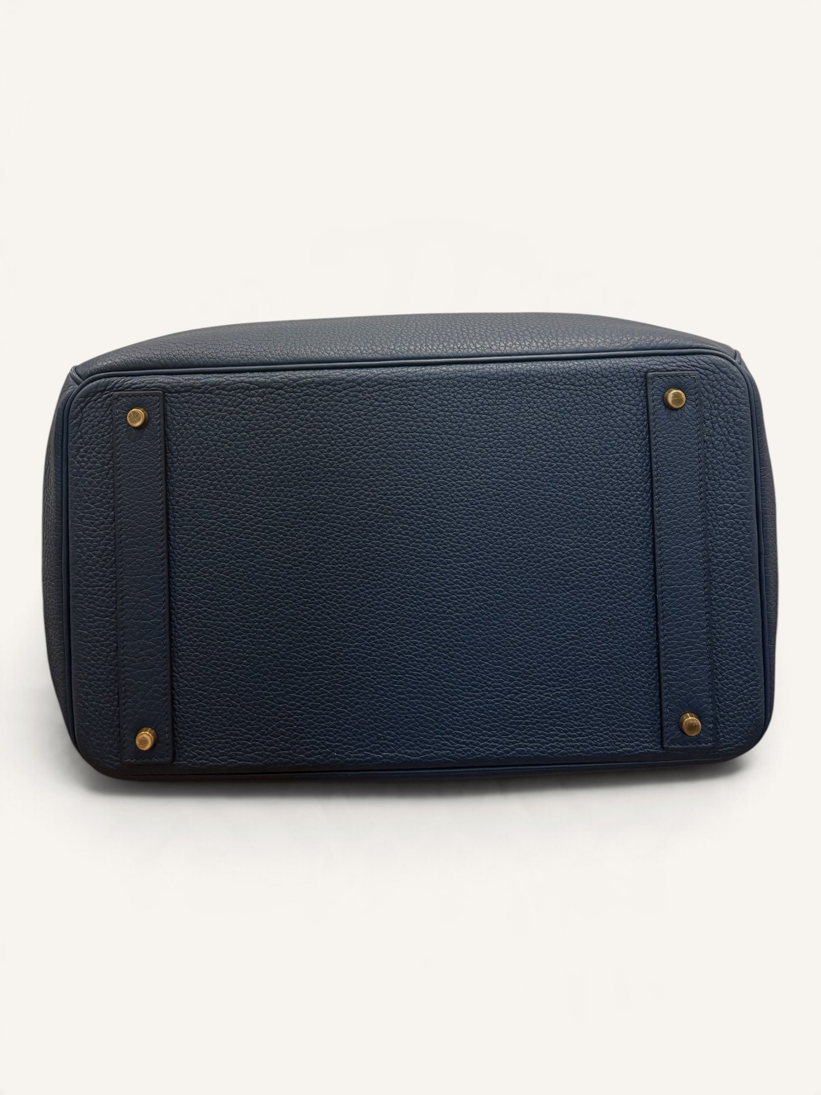 # Hermès HAC 40 Bleu de Prusse en cuir Togo, finitions Gold – 2015 Ce **HAC 40 Bleu de Prusse** en cuir Togo date de **2015**. Il se distingue par son magnifique bleu profond, associé à des **finitions Gold** qui apportent un contraste chaleureux. Présenté en **très bon état général**, cet exemplaire possède uniquement de légères traces d'utilisation au niveau des coins. Son format 40 et sa silhouette caractéristique lui confèrent une présence remarquable. **Dimensions : format 40 cm – dimensions complètes à compléter** **Matière : cuir Togo** **Couleur : Bleu de Prusse** **Finitions : Gold** **Année : 2015** **État : très bon état général, légères traces aux coins** Cette configuration associe l'élégance d'une couleur profonde à la texture du cuir Togo. Ainsi, le sac conserve une esthétique intemporelle tout en se distinguant des coloris plus traditionnels. --- ## HAC 40 Bleu de Prusse : une couleur profonde et élégante Le **Bleu de Prusse** fait partie des tonalités sombres particulièrement intéressantes de la palette Hermès. Sa profondeur lui donne une élégance proche de celle d'un bleu nuit. Cependant, ses nuances peuvent évoluer selon la lumière. Sous un éclairage naturel, le cuir peut révéler davantage de bleu. En revanche, dans une ambiance plus sombre, sa couleur apparaît plus intense. Cette richesse visuelle apporte une personnalité particulière au sac. De plus, le Bleu de Prusse s'associe facilement au noir, au gris, au beige et aux tons naturels. Il constitue donc une belle alternative aux grands sacs Hermès noirs ou marron. ## Le cuir Togo : une matière emblématique Le **cuir Togo** est apprécié pour son grain visible et son toucher souple. Il offre un équilibre intéressant entre structure et souplesse. Sur un grand format comme le HAC 40, cette matière permet de mettre en valeur les volumes du sac. Par ailleurs, sa surface grainée rend généralement les petites marques moins apparentes que sur certains cuirs lisses. Le résultat est un sac agréable à utiliser, tout en conservant une belle présence. Associé au Bleu de Prusse, le Togo révèle également de subtils jeux de lumière. ## Des finitions Gold au contraste raffiné Les **finitions Gold** jouent un rôle essentiel dans l'esthétique de cet exemplaire. Leur tonalité dorée contraste avec le bleu profond du cuir. Ainsi, les éléments métalliques deviennent de véritables détails décoratifs. Cette association apporte davantage de chaleur qu'une configuration accompagnée de finitions Palladium. De plus, le contraste entre le bleu et l'or renforce le caractère sophistiqué de ce HAC 40. Il s'agit d'une combinaison particulièrement élégante pour un grand sac de maroquinerie. ## Hermès HAC 40 : une silhouette historique Le **HAC**, ou *Haut à Courroies*, occupe une place particulière dans l'histoire d'Hermès. Créé à la fin du XIXe siècle, il était initialement destiné au transport des équipements équestres. Son nom fait référence à sa silhouette haute et à son système de fermeture à courroies. Au fil du temps, le modèle a évolué pour devenir une pièce emblématique de la maroquinerie de voyage Hermès. Aujourd'hui, il séduit aussi bien les collectionneurs que les amateurs de grands sacs de luxe. Son format généreux et sa structure reconnaissable lui donnent une identité distincte du Birkin. ## Un HAC 40 datant de 2015 Cet exemplaire a été fabriqué en **2015**. Il possède donc plus de dix années d'ancienneté. Malgré son âge, il est conservé dans un **très bon état général**. Seules de légères traces sont visibles au niveau des coins. Ces marques correspondent à une utilisation normale et restent limitées. Par ailleurs, elles sont clairement présentées afin de permettre une acquisition en toute transparence. ## Très bon état avec de légères traces aux coins L'état de conservation constitue un critère essentiel pour un sac Hermès d'occasion. Ce **HAC 40 Bleu de Prusse** est proposé en très bon état général. Le cuir Togo conserve une belle présentation. Cependant, quelques légères marques sont présentes aux coins. Ces zones sont naturellement exposées aux frottements lors de l'utilisation d'un sac. Nos photographies détaillées permettent donc d'apprécier précisément leur importance. Ainsi, l'acheteur dispose d'une description fidèle de l'état réel de la pièce. ## Le format HAC 40 : volume et élégance Le **format 40** offre un volume généreux. Il permet de transporter facilement de nombreux effets personnels. Ce sac peut notamment accueillir : - Un portefeuille. - Un téléphone. - Des lunettes. - Une pochette. - Des documents. - Une tablette. - Divers accessoires personnels. De plus, sa silhouette haute lui donne une présence plus affirmée que celle d'un sac à main classique. Il peut donc être envisagé comme un grand sac quotidien ou un élégant compagnon de déplacement. ## Un grand sac Hermès au caractère affirmé Le HAC 40 possède une esthétique immédiatement reconnaissable. Sa silhouette structurée et ses proportions généreuses lui confèrent une allure particulière. Sur cet exemplaire, le cuir Togo Bleu de Prusse apporte davantage de souplesse visuelle. En parallèle, les finitions Gold soulignent les lignes du sac. Ainsi, l'ensemble reste élégant malgré son volume important. Cette combinaison conviendra particulièrement aux amateurs de pièces Hermès discrètes par leur couleur, mais remarquables par leur format. ## Pourquoi choisir un HAC 40 Bleu de Prusse ? Cet exemplaire réunit plusieurs caractéristiques intéressantes : - **Modèle :** Hermès Haut à Courroies 40. - **Année :** 2015. - **Matière :** cuir Togo. - **Couleur :** Bleu de Prusse. - **Finitions :** Gold. - **État :** très bon état général. - **À noter :** légères traces d'utilisation aux coins. - **Format :** 40 cm. Cette configuration se distingue notamment par son équilibre entre couleur profonde, cuir grainé et finitions dorées. Elle constitue donc une belle option pour enrichir une collection Hermès ou acquérir un grand sac élégant. ## Une alternative aux HAC noirs et marron Les grands sacs Hermès sont souvent recherchés dans des couleurs classiques. Le noir, le Gold ou l'Ébène restent naturellement des choix intemporels. Toutefois, le Bleu de Prusse permet d'apporter davantage de personnalité sans choisir une couleur trop vive. Son intensité reste discrète. De plus, les finitions Gold créent un contraste qui souligne parfaitement le bleu du cuir. Ainsi, ce HAC 40 constitue une alternative particulièrement intéressante aux configurations traditionnelles. ## Un sac Hermès à porter et à conserver Grâce à son cuir Togo et à son format généreux, cet exemplaire peut être utilisé régulièrement. Il peut accompagner un vestiaire élégant ou plus décontracté. Cependant, sa couleur particulière lui donne également un intérêt pour les amateurs de configurations Hermès moins courantes. Le Bleu de Prusse permet notamment de varier une collection composée de sacs noirs, marron ou beiges. Ce HAC 40 peut donc aussi bien devenir un sac personnel qu'une belle pièce de collection. ## Pourquoi acheter votre HAC Hermès chez The Vintage Traveler ? Chez **The Vintage Traveler**, nous sélectionnons des sacs Hermès vintage et d'occasion pour leur authenticité, leur qualité et leurs caractéristiques. Chaque pièce est examinée avec attention afin de présenter précisément son état et ses particularités. ### Nos garanties ✔ **Magasin physique situé au Marché Paul Bert Serpette**, au cœur des Puces de Saint-Ouen. ✔ Sac **expertisé et certifié authentique** par un spécialiste du luxe vintage et d'occasion. ✔ Certificat d'authenticité fourni avec votre achat. ✔ Photographies détaillées et fidèles à l'état réel du sac. ✔ Description transparente des légères traces présentes aux coins. ✔ Accompagnement personnalisé avant et après votre achat. ✔ Expédition internationale rapide, sécurisée et assurée. --- ## Caractéristiques du Hermès HAC 40 **Maison :** Hermès **Modèle :** Haut à Courroies – HAC 40 **Année :** 2015 **Matière :** Cuir Togo **Couleur :** Bleu de Prusse **Finitions :** Gold **Format :** 40 cm **Dimensions complètes :** à compléter **État :** Très bon état général **À noter :** Légères traces d'utilisation aux coins --- ## Un élégant HAC 40 Bleu de Prusse de 2015 Ce **HAC 40 Bleu de Prusse** en cuir Togo constitue une superbe interprétation du célèbre Haut à Courroies Hermès. Sa couleur profonde, associée aux **finitions Gold**, lui donne une esthétique particulièrement raffinée. Datant de **2015**, cet exemplaire est conservé dans un **très bon état général**, avec seulement de légères traces aux coins. Enfin, son format 40 offre un volume généreux tout en conservant la silhouette emblématique du HAC. Une belle pièce pour les amateurs de **sacs Hermès d'occasion**, de grands formats et de couleurs sophistiquées.