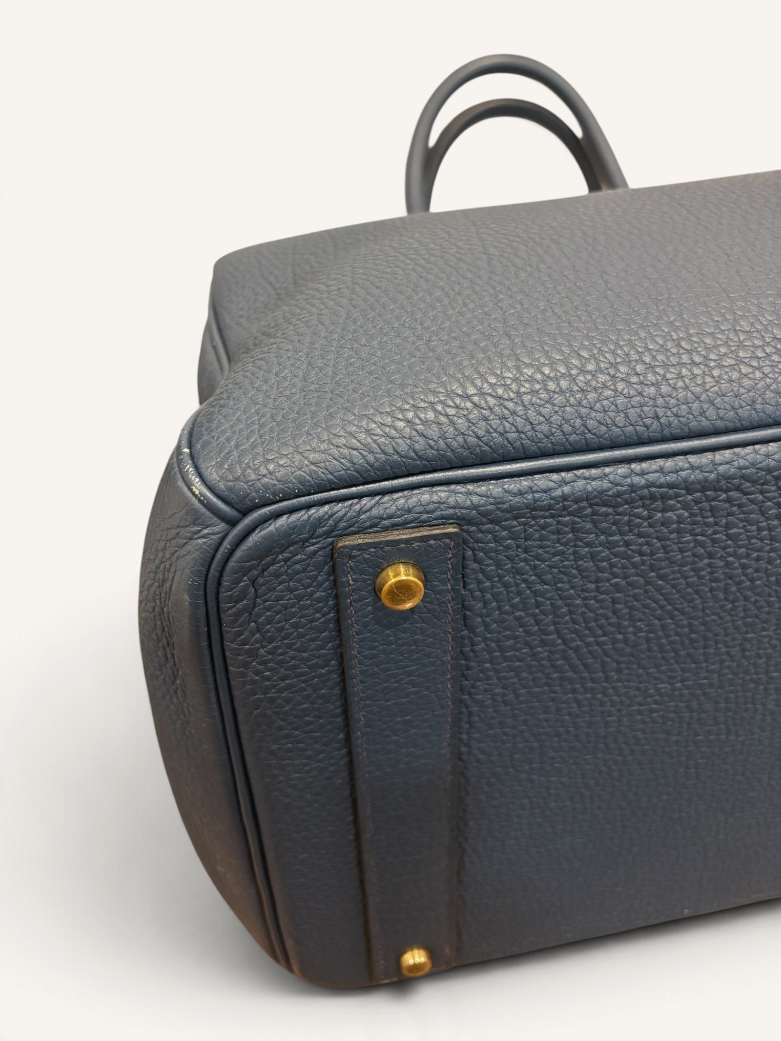 # Hermès HAC 40 Bleu de Prusse en cuir Togo, finitions Gold – 2015 Ce **HAC 40 Bleu de Prusse** en cuir Togo date de **2015**. Il se distingue par son magnifique bleu profond, associé à des **finitions Gold** qui apportent un contraste chaleureux. Présenté en **très bon état général**, cet exemplaire possède uniquement de légères traces d'utilisation au niveau des coins. Son format 40 et sa silhouette caractéristique lui confèrent une présence remarquable. **Dimensions : format 40 cm – dimensions complètes à compléter** **Matière : cuir Togo** **Couleur : Bleu de Prusse** **Finitions : Gold** **Année : 2015** **État : très bon état général, légères traces aux coins** Cette configuration associe l'élégance d'une couleur profonde à la texture du cuir Togo. Ainsi, le sac conserve une esthétique intemporelle tout en se distinguant des coloris plus traditionnels. --- ## HAC 40 Bleu de Prusse : une couleur profonde et élégante Le **Bleu de Prusse** fait partie des tonalités sombres particulièrement intéressantes de la palette Hermès. Sa profondeur lui donne une élégance proche de celle d'un bleu nuit. Cependant, ses nuances peuvent évoluer selon la lumière. Sous un éclairage naturel, le cuir peut révéler davantage de bleu. En revanche, dans une ambiance plus sombre, sa couleur apparaît plus intense. Cette richesse visuelle apporte une personnalité particulière au sac. De plus, le Bleu de Prusse s'associe facilement au noir, au gris, au beige et aux tons naturels. Il constitue donc une belle alternative aux grands sacs Hermès noirs ou marron. ## Le cuir Togo : une matière emblématique Le **cuir Togo** est apprécié pour son grain visible et son toucher souple. Il offre un équilibre intéressant entre structure et souplesse. Sur un grand format comme le HAC 40, cette matière permet de mettre en valeur les volumes du sac. Par ailleurs, sa surface grainée rend généralement les petites marques moins apparentes que sur certains cuirs lisses. Le résultat est un sac agréable à utiliser, tout en conservant une belle présence. Associé au Bleu de Prusse, le Togo révèle également de subtils jeux de lumière. ## Des finitions Gold au contraste raffiné Les **finitions Gold** jouent un rôle essentiel dans l'esthétique de cet exemplaire. Leur tonalité dorée contraste avec le bleu profond du cuir. Ainsi, les éléments métalliques deviennent de véritables détails décoratifs. Cette association apporte davantage de chaleur qu'une configuration accompagnée de finitions Palladium. De plus, le contraste entre le bleu et l'or renforce le caractère sophistiqué de ce HAC 40. Il s'agit d'une combinaison particulièrement élégante pour un grand sac de maroquinerie. ## Hermès HAC 40 : une silhouette historique Le **HAC**, ou *Haut à Courroies*, occupe une place particulière dans l'histoire d'Hermès. Créé à la fin du XIXe siècle, il était initialement destiné au transport des équipements équestres. Son nom fait référence à sa silhouette haute et à son système de fermeture à courroies. Au fil du temps, le modèle a évolué pour devenir une pièce emblématique de la maroquinerie de voyage Hermès. Aujourd'hui, il séduit aussi bien les collectionneurs que les amateurs de grands sacs de luxe. Son format généreux et sa structure reconnaissable lui donnent une identité distincte du Birkin. ## Un HAC 40 datant de 2015 Cet exemplaire a été fabriqué en **2015**. Il possède donc plus de dix années d'ancienneté. Malgré son âge, il est conservé dans un **très bon état général**. Seules de légères traces sont visibles au niveau des coins. Ces marques correspondent à une utilisation normale et restent limitées. Par ailleurs, elles sont clairement présentées afin de permettre une acquisition en toute transparence. ## Très bon état avec de légères traces aux coins L'état de conservation constitue un critère essentiel pour un sac Hermès d'occasion. Ce **HAC 40 Bleu de Prusse** est proposé en très bon état général. Le cuir Togo conserve une belle présentation. Cependant, quelques légères marques sont présentes aux coins. Ces zones sont naturellement exposées aux frottements lors de l'utilisation d'un sac. Nos photographies détaillées permettent donc d'apprécier précisément leur importance. Ainsi, l'acheteur dispose d'une description fidèle de l'état réel de la pièce. ## Le format HAC 40 : volume et élégance Le **format 40** offre un volume généreux. Il permet de transporter facilement de nombreux effets personnels. Ce sac peut notamment accueillir : - Un portefeuille. - Un téléphone. - Des lunettes. - Une pochette. - Des documents. - Une tablette. - Divers accessoires personnels. De plus, sa silhouette haute lui donne une présence plus affirmée que celle d'un sac à main classique. Il peut donc être envisagé comme un grand sac quotidien ou un élégant compagnon de déplacement. ## Un grand sac Hermès au caractère affirmé Le HAC 40 possède une esthétique immédiatement reconnaissable. Sa silhouette structurée et ses proportions généreuses lui confèrent une allure particulière. Sur cet exemplaire, le cuir Togo Bleu de Prusse apporte davantage de souplesse visuelle. En parallèle, les finitions Gold soulignent les lignes du sac. Ainsi, l'ensemble reste élégant malgré son volume important. Cette combinaison conviendra particulièrement aux amateurs de pièces Hermès discrètes par leur couleur, mais remarquables par leur format. ## Pourquoi choisir un HAC 40 Bleu de Prusse ? Cet exemplaire réunit plusieurs caractéristiques intéressantes : - **Modèle :** Hermès Haut à Courroies 40. - **Année :** 2015. - **Matière :** cuir Togo. - **Couleur :** Bleu de Prusse. - **Finitions :** Gold. - **État :** très bon état général. - **À noter :** légères traces d'utilisation aux coins. - **Format :** 40 cm. Cette configuration se distingue notamment par son équilibre entre couleur profonde, cuir grainé et finitions dorées. Elle constitue donc une belle option pour enrichir une collection Hermès ou acquérir un grand sac élégant. ## Une alternative aux HAC noirs et marron Les grands sacs Hermès sont souvent recherchés dans des couleurs classiques. Le noir, le Gold ou l'Ébène restent naturellement des choix intemporels. Toutefois, le Bleu de Prusse permet d'apporter davantage de personnalité sans choisir une couleur trop vive. Son intensité reste discrète. De plus, les finitions Gold créent un contraste qui souligne parfaitement le bleu du cuir. Ainsi, ce HAC 40 constitue une alternative particulièrement intéressante aux configurations traditionnelles. ## Un sac Hermès à porter et à conserver Grâce à son cuir Togo et à son format généreux, cet exemplaire peut être utilisé régulièrement. Il peut accompagner un vestiaire élégant ou plus décontracté. Cependant, sa couleur particulière lui donne également un intérêt pour les amateurs de configurations Hermès moins courantes. Le Bleu de Prusse permet notamment de varier une collection composée de sacs noirs, marron ou beiges. Ce HAC 40 peut donc aussi bien devenir un sac personnel qu'une belle pièce de collection. ## Pourquoi acheter votre HAC Hermès chez The Vintage Traveler ? Chez **The Vintage Traveler**, nous sélectionnons des sacs Hermès vintage et d'occasion pour leur authenticité, leur qualité et leurs caractéristiques. Chaque pièce est examinée avec attention afin de présenter précisément son état et ses particularités. ### Nos garanties ✔ **Magasin physique situé au Marché Paul Bert Serpette**, au cœur des Puces de Saint-Ouen. ✔ Sac **expertisé et certifié authentique** par un spécialiste du luxe vintage et d'occasion. ✔ Certificat d'authenticité fourni avec votre achat. ✔ Photographies détaillées et fidèles à l'état réel du sac. ✔ Description transparente des légères traces présentes aux coins. ✔ Accompagnement personnalisé avant et après votre achat. ✔ Expédition internationale rapide, sécurisée et assurée. --- ## Caractéristiques du Hermès HAC 40 **Maison :** Hermès **Modèle :** Haut à Courroies – HAC 40 **Année :** 2015 **Matière :** Cuir Togo **Couleur :** Bleu de Prusse **Finitions :** Gold **Format :** 40 cm **Dimensions complètes :** à compléter **État :** Très bon état général **À noter :** Légères traces d'utilisation aux coins --- ## Un élégant HAC 40 Bleu de Prusse de 2015 Ce **HAC 40 Bleu de Prusse** en cuir Togo constitue une superbe interprétation du célèbre Haut à Courroies Hermès. Sa couleur profonde, associée aux **finitions Gold**, lui donne une esthétique particulièrement raffinée. Datant de **2015**, cet exemplaire est conservé dans un **très bon état général**, avec seulement de légères traces aux coins. Enfin, son format 40 offre un volume généreux tout en conservant la silhouette emblématique du HAC. Une belle pièce pour les amateurs de **sacs Hermès d'occasion**, de grands formats et de couleurs sophistiquées.