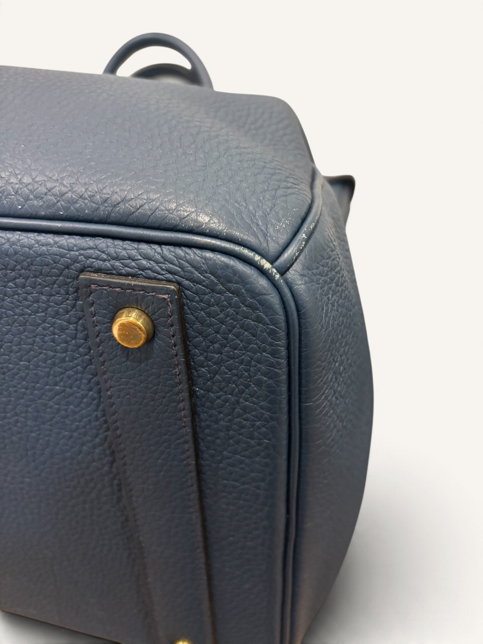 # Hermès HAC 40 Bleu de Prusse en cuir Togo, finitions Gold – 2015 Ce **HAC 40 Bleu de Prusse** en cuir Togo date de **2015**. Il se distingue par son magnifique bleu profond, associé à des **finitions Gold** qui apportent un contraste chaleureux. Présenté en **très bon état général**, cet exemplaire possède uniquement de légères traces d'utilisation au niveau des coins. Son format 40 et sa silhouette caractéristique lui confèrent une présence remarquable. **Dimensions : format 40 cm – dimensions complètes à compléter** **Matière : cuir Togo** **Couleur : Bleu de Prusse** **Finitions : Gold** **Année : 2015** **État : très bon état général, légères traces aux coins** Cette configuration associe l'élégance d'une couleur profonde à la texture du cuir Togo. Ainsi, le sac conserve une esthétique intemporelle tout en se distinguant des coloris plus traditionnels. --- ## HAC 40 Bleu de Prusse : une couleur profonde et élégante Le **Bleu de Prusse** fait partie des tonalités sombres particulièrement intéressantes de la palette Hermès. Sa profondeur lui donne une élégance proche de celle d'un bleu nuit. Cependant, ses nuances peuvent évoluer selon la lumière. Sous un éclairage naturel, le cuir peut révéler davantage de bleu. En revanche, dans une ambiance plus sombre, sa couleur apparaît plus intense. Cette richesse visuelle apporte une personnalité particulière au sac. De plus, le Bleu de Prusse s'associe facilement au noir, au gris, au beige et aux tons naturels. Il constitue donc une belle alternative aux grands sacs Hermès noirs ou marron. ## Le cuir Togo : une matière emblématique Le **cuir Togo** est apprécié pour son grain visible et son toucher souple. Il offre un équilibre intéressant entre structure et souplesse. Sur un grand format comme le HAC 40, cette matière permet de mettre en valeur les volumes du sac. Par ailleurs, sa surface grainée rend généralement les petites marques moins apparentes que sur certains cuirs lisses. Le résultat est un sac agréable à utiliser, tout en conservant une belle présence. Associé au Bleu de Prusse, le Togo révèle également de subtils jeux de lumière. ## Des finitions Gold au contraste raffiné Les **finitions Gold** jouent un rôle essentiel dans l'esthétique de cet exemplaire. Leur tonalité dorée contraste avec le bleu profond du cuir. Ainsi, les éléments métalliques deviennent de véritables détails décoratifs. Cette association apporte davantage de chaleur qu'une configuration accompagnée de finitions Palladium. De plus, le contraste entre le bleu et l'or renforce le caractère sophistiqué de ce HAC 40. Il s'agit d'une combinaison particulièrement élégante pour un grand sac de maroquinerie. ## Hermès HAC 40 : une silhouette historique Le **HAC**, ou *Haut à Courroies*, occupe une place particulière dans l'histoire d'Hermès. Créé à la fin du XIXe siècle, il était initialement destiné au transport des équipements équestres. Son nom fait référence à sa silhouette haute et à son système de fermeture à courroies. Au fil du temps, le modèle a évolué pour devenir une pièce emblématique de la maroquinerie de voyage Hermès. Aujourd'hui, il séduit aussi bien les collectionneurs que les amateurs de grands sacs de luxe. Son format généreux et sa structure reconnaissable lui donnent une identité distincte du Birkin. ## Un HAC 40 datant de 2015 Cet exemplaire a été fabriqué en **2015**. Il possède donc plus de dix années d'ancienneté. Malgré son âge, il est conservé dans un **très bon état général**. Seules de légères traces sont visibles au niveau des coins. Ces marques correspondent à une utilisation normale et restent limitées. Par ailleurs, elles sont clairement présentées afin de permettre une acquisition en toute transparence. ## Très bon état avec de légères traces aux coins L'état de conservation constitue un critère essentiel pour un sac Hermès d'occasion. Ce **HAC 40 Bleu de Prusse** est proposé en très bon état général. Le cuir Togo conserve une belle présentation. Cependant, quelques légères marques sont présentes aux coins. Ces zones sont naturellement exposées aux frottements lors de l'utilisation d'un sac. Nos photographies détaillées permettent donc d'apprécier précisément leur importance. Ainsi, l'acheteur dispose d'une description fidèle de l'état réel de la pièce. ## Le format HAC 40 : volume et élégance Le **format 40** offre un volume généreux. Il permet de transporter facilement de nombreux effets personnels. Ce sac peut notamment accueillir : - Un portefeuille. - Un téléphone. - Des lunettes. - Une pochette. - Des documents. - Une tablette. - Divers accessoires personnels. De plus, sa silhouette haute lui donne une présence plus affirmée que celle d'un sac à main classique. Il peut donc être envisagé comme un grand sac quotidien ou un élégant compagnon de déplacement. ## Un grand sac Hermès au caractère affirmé Le HAC 40 possède une esthétique immédiatement reconnaissable. Sa silhouette structurée et ses proportions généreuses lui confèrent une allure particulière. Sur cet exemplaire, le cuir Togo Bleu de Prusse apporte davantage de souplesse visuelle. En parallèle, les finitions Gold soulignent les lignes du sac. Ainsi, l'ensemble reste élégant malgré son volume important. Cette combinaison conviendra particulièrement aux amateurs de pièces Hermès discrètes par leur couleur, mais remarquables par leur format. ## Pourquoi choisir un HAC 40 Bleu de Prusse ? Cet exemplaire réunit plusieurs caractéristiques intéressantes : - **Modèle :** Hermès Haut à Courroies 40. - **Année :** 2015. - **Matière :** cuir Togo. - **Couleur :** Bleu de Prusse. - **Finitions :** Gold. - **État :** très bon état général. - **À noter :** légères traces d'utilisation aux coins. - **Format :** 40 cm. Cette configuration se distingue notamment par son équilibre entre couleur profonde, cuir grainé et finitions dorées. Elle constitue donc une belle option pour enrichir une collection Hermès ou acquérir un grand sac élégant. ## Une alternative aux HAC noirs et marron Les grands sacs Hermès sont souvent recherchés dans des couleurs classiques. Le noir, le Gold ou l'Ébène restent naturellement des choix intemporels. Toutefois, le Bleu de Prusse permet d'apporter davantage de personnalité sans choisir une couleur trop vive. Son intensité reste discrète. De plus, les finitions Gold créent un contraste qui souligne parfaitement le bleu du cuir. Ainsi, ce HAC 40 constitue une alternative particulièrement intéressante aux configurations traditionnelles. ## Un sac Hermès à porter et à conserver Grâce à son cuir Togo et à son format généreux, cet exemplaire peut être utilisé régulièrement. Il peut accompagner un vestiaire élégant ou plus décontracté. Cependant, sa couleur particulière lui donne également un intérêt pour les amateurs de configurations Hermès moins courantes. Le Bleu de Prusse permet notamment de varier une collection composée de sacs noirs, marron ou beiges. Ce HAC 40 peut donc aussi bien devenir un sac personnel qu'une belle pièce de collection. ## Pourquoi acheter votre HAC Hermès chez The Vintage Traveler ? Chez **The Vintage Traveler**, nous sélectionnons des sacs Hermès vintage et d'occasion pour leur authenticité, leur qualité et leurs caractéristiques. Chaque pièce est examinée avec attention afin de présenter précisément son état et ses particularités. ### Nos garanties ✔ **Magasin physique situé au Marché Paul Bert Serpette**, au cœur des Puces de Saint-Ouen. ✔ Sac **expertisé et certifié authentique** par un spécialiste du luxe vintage et d'occasion. ✔ Certificat d'authenticité fourni avec votre achat. ✔ Photographies détaillées et fidèles à l'état réel du sac. ✔ Description transparente des légères traces présentes aux coins. ✔ Accompagnement personnalisé avant et après votre achat. ✔ Expédition internationale rapide, sécurisée et assurée. --- ## Caractéristiques du Hermès HAC 40 **Maison :** Hermès **Modèle :** Haut à Courroies – HAC 40 **Année :** 2015 **Matière :** Cuir Togo **Couleur :** Bleu de Prusse **Finitions :** Gold **Format :** 40 cm **Dimensions complètes :** à compléter **État :** Très bon état général **À noter :** Légères traces d'utilisation aux coins --- ## Un élégant HAC 40 Bleu de Prusse de 2015 Ce **HAC 40 Bleu de Prusse** en cuir Togo constitue une superbe interprétation du célèbre Haut à Courroies Hermès. Sa couleur profonde, associée aux **finitions Gold**, lui donne une esthétique particulièrement raffinée. Datant de **2015**, cet exemplaire est conservé dans un **très bon état général**, avec seulement de légères traces aux coins. Enfin, son format 40 offre un volume généreux tout en conservant la silhouette emblématique du HAC. Une belle pièce pour les amateurs de **sacs Hermès d'occasion**, de grands formats et de couleurs sophistiquées.